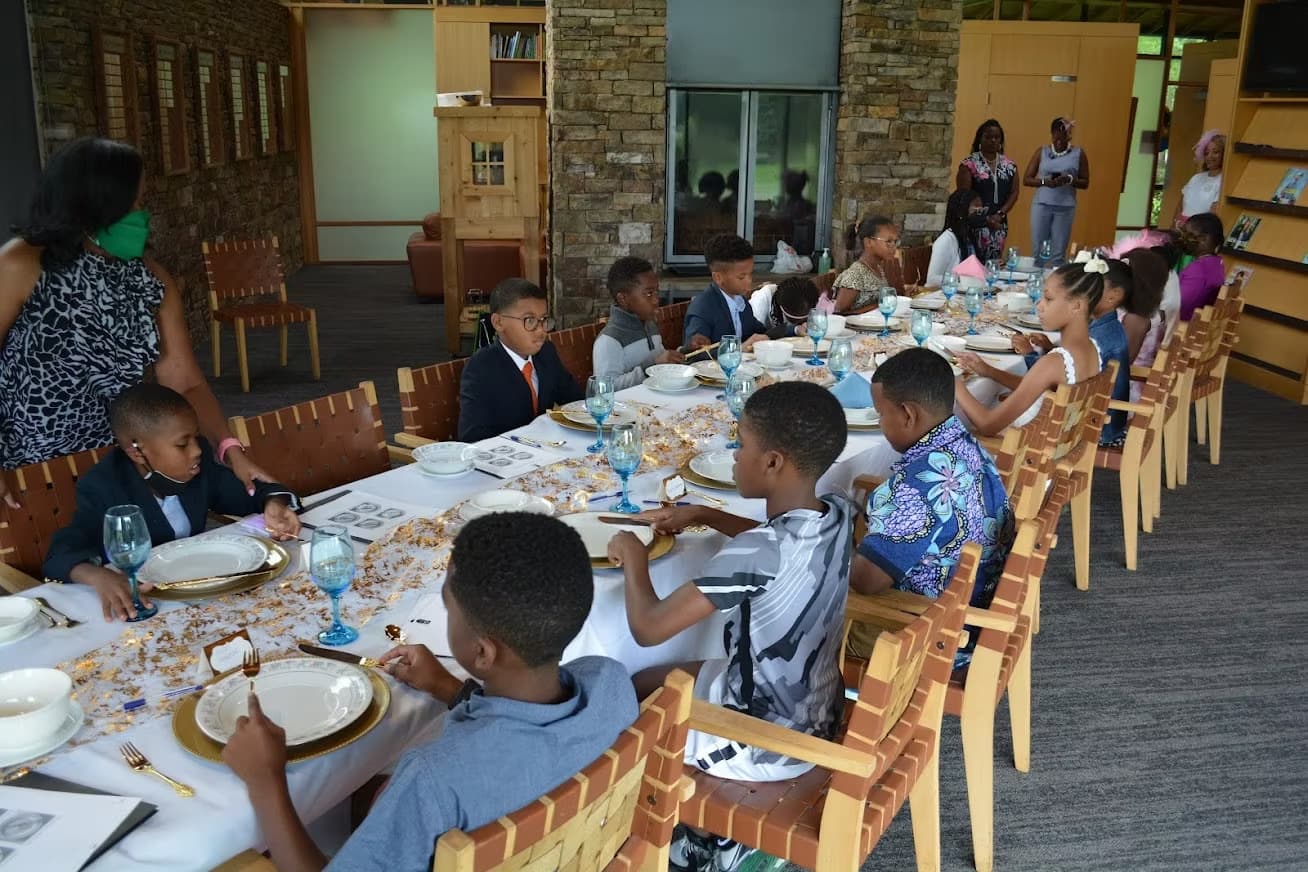 Young students gathered around a long dining table set for an etiquette class.